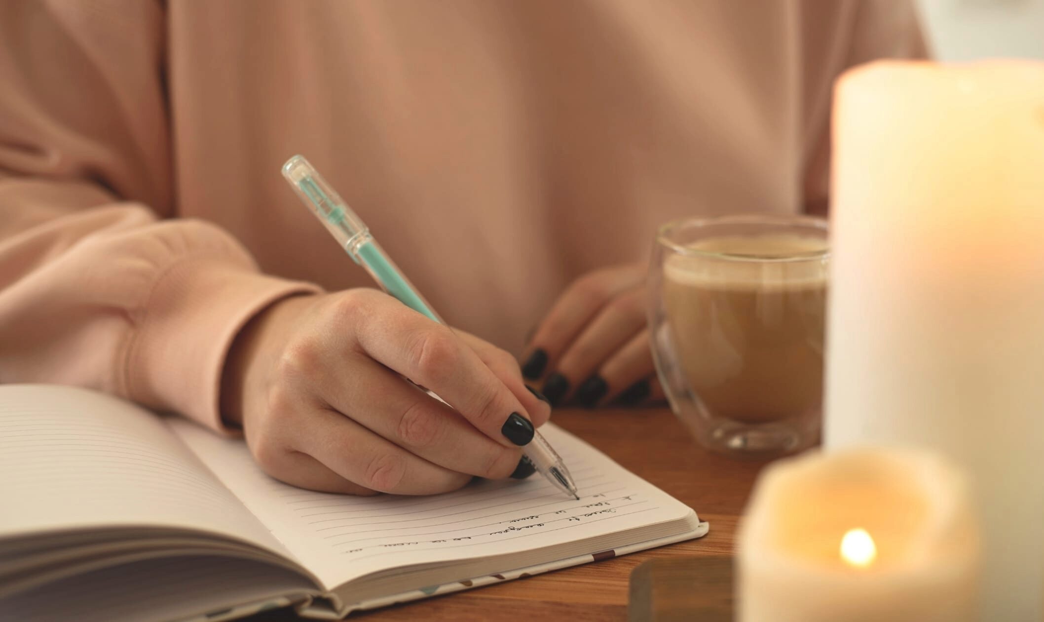 Mom writing in a notebook with a cup of coffee nearby, reflecting during a quiet moment