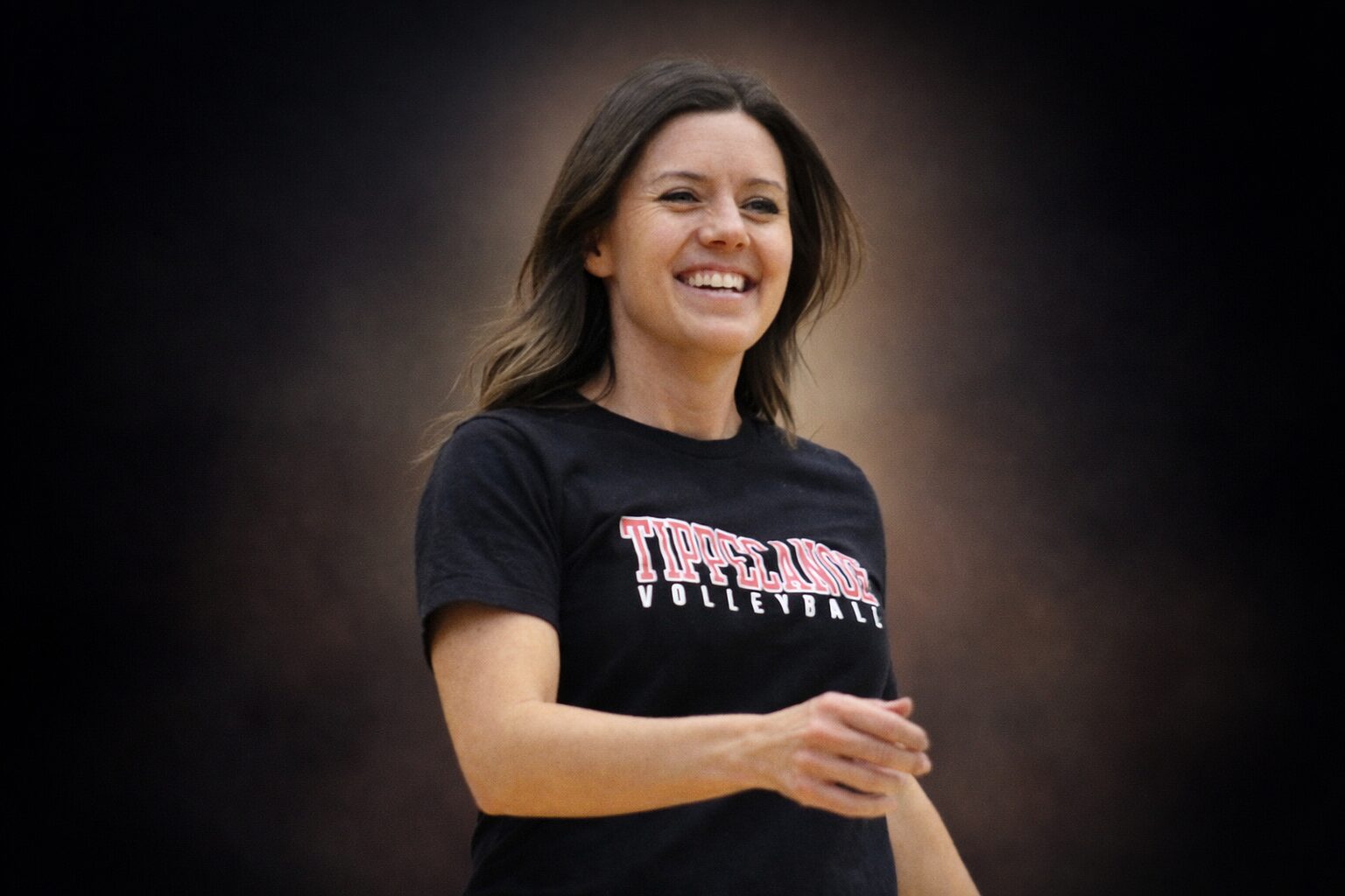 Ashley Flynn smiling while coaching volleyball, reflecting the light and joy she brought to her community